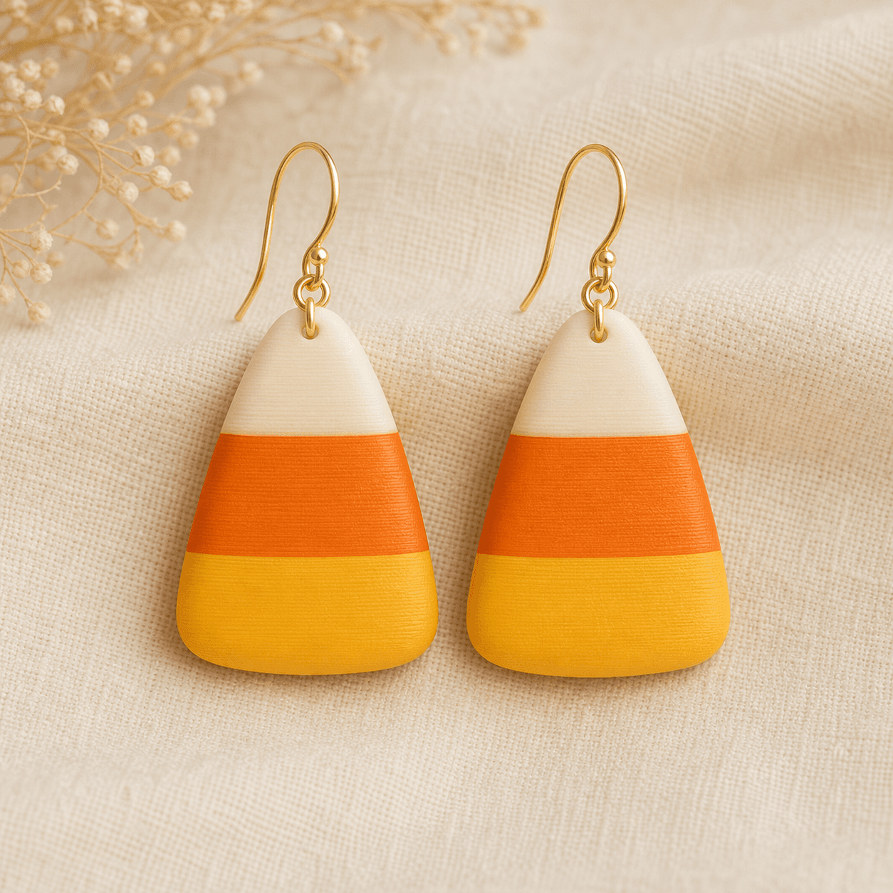 Candy Corn Earrings — 3D-printed resin drop earrings shaped like oversized candy corn kernels with cream, orange, and yellow stripes