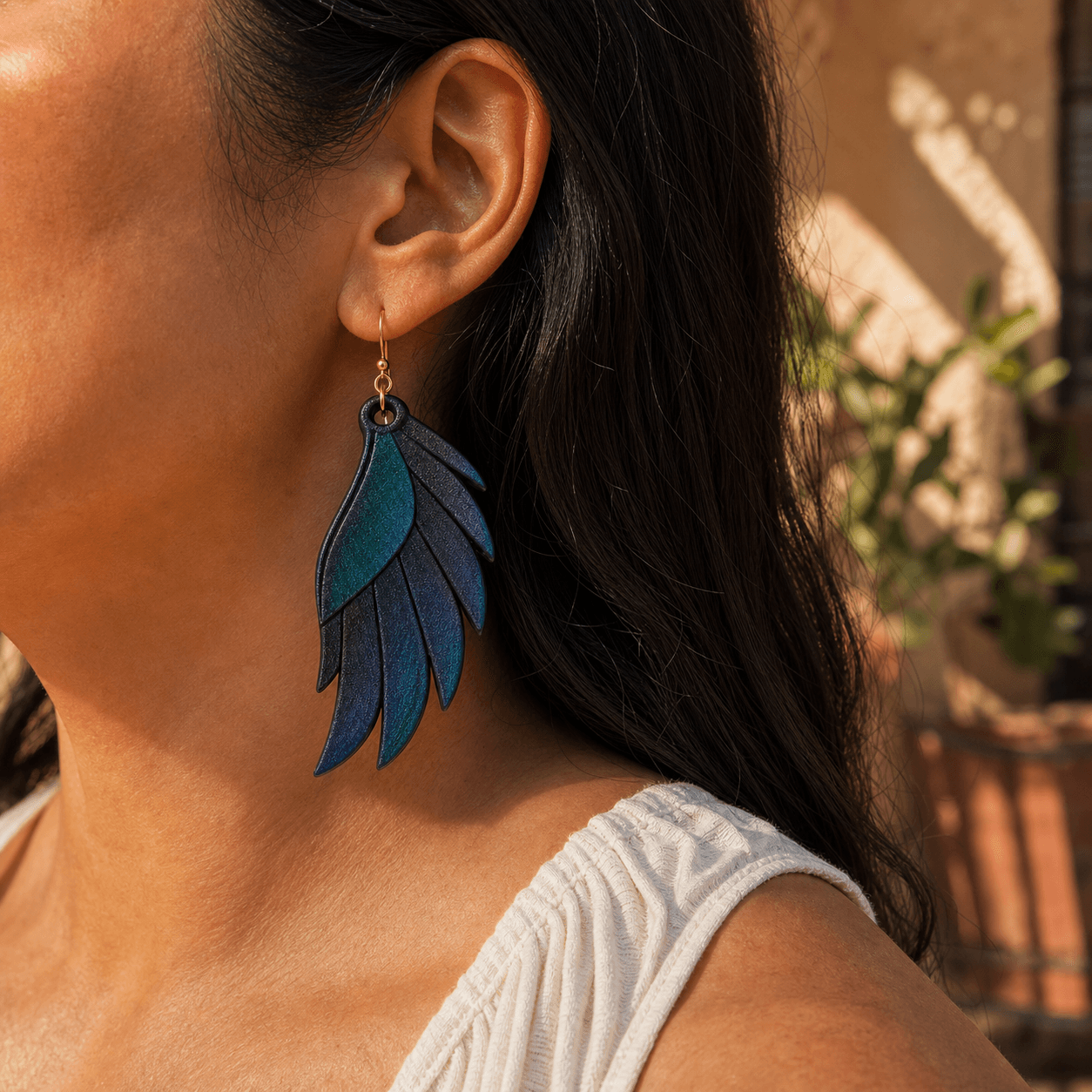 Grackle Wing Earring worn, showing the roughly 2-inch drop length and iridescent shimmer in sunlight