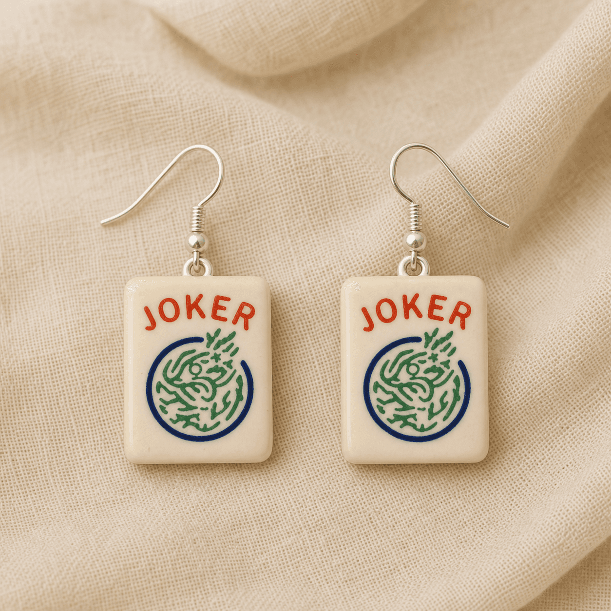 Mahjong Joker Tile Earrings — 3D-printed cream resin mahjong joker tiles with red JOKER lettering above a green dragon medallion in a blue ring, on silver-tone stainless steel ear wires